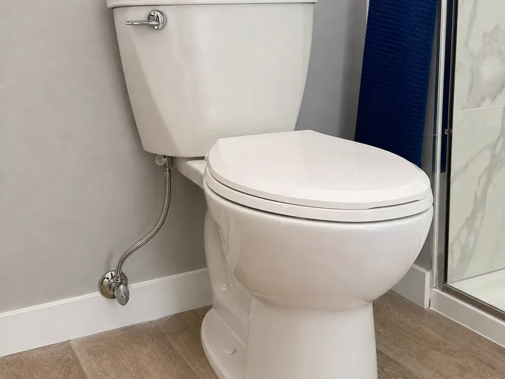 Newly installed two-piece toilet with a clean base finish and straight braided supply line